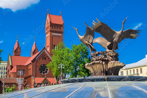 Church of Saints Simon and Helena (Red Church) and sculpture of bronze storks in Minsk, Belarus.
