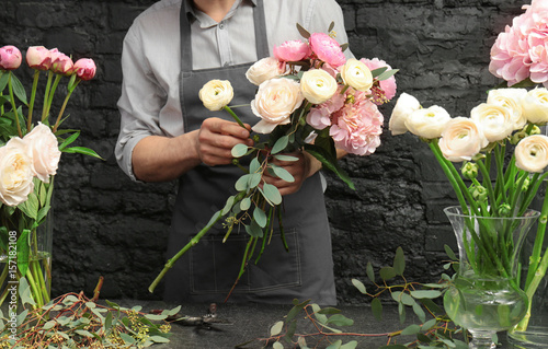 Male florist creating beautiful bouquet in flower shop, close up