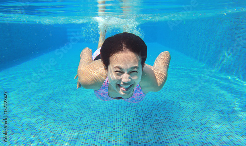 Underwater shot of young woman diving into the swimming pool.