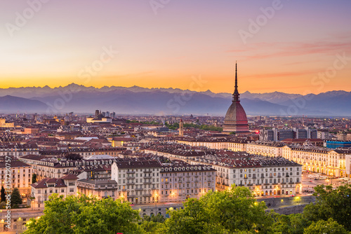 Cityscape of Torino (Turin, Italy) at dusk with colorful moody sky. The Mole Antonelliana towering on the illuminated city below.