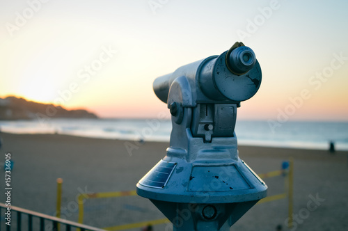 Touristic payment observation monocular pointing at the ocean shoreline sunset outdoors background