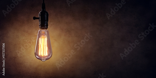 Vintage Hanging Light Bulb Over Dark Wall 