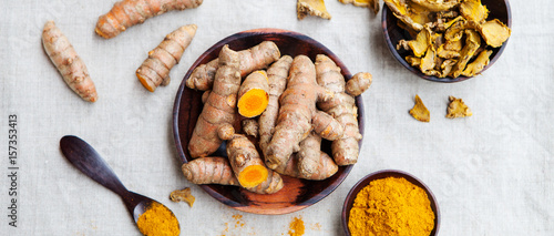 Fresh and dried turmeric roots in a wooden bowl