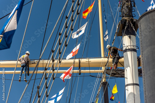 men climbing ships mast on glorious sunny day