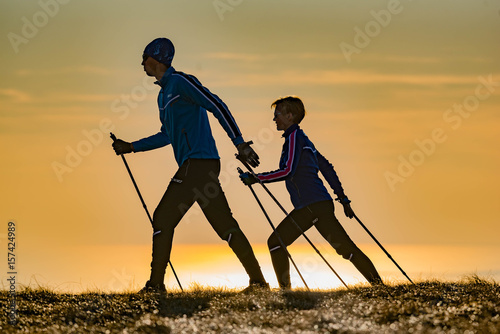 a couple doing Nordic walking exercise on a sunset