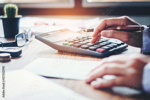 Businessman's hands with calculator and cost at the office and Financial data analyzing counting on wood desk