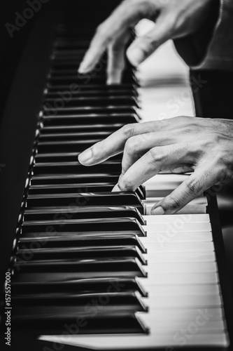 male musician hands playing on piano keys, black and white. music background