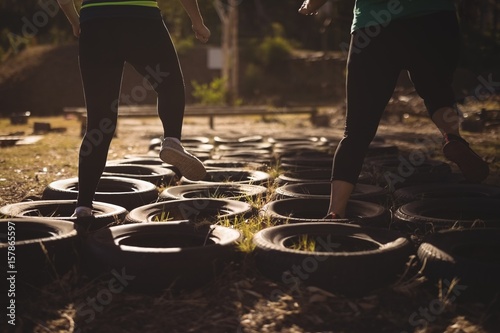 Low section of friends running over tires during obstacle course