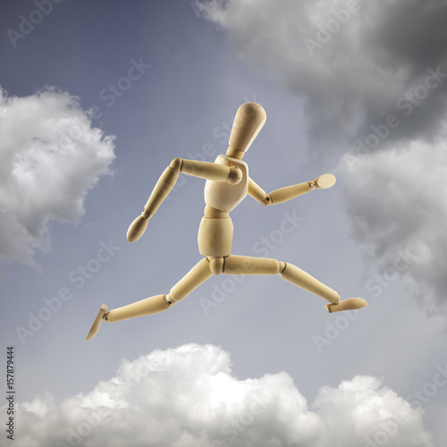 Wooden mannequin in the dramatic sky. Running and jumping concept