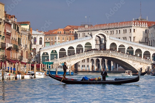 A gondola crossing the Grand Canal right in front of the Rialto Bridge, one of the most recognizable Venetian landmarks Venice, Veneto Italy Europe