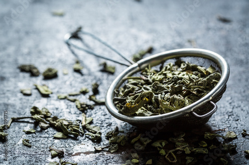 Fresh green tea in old metal strainer