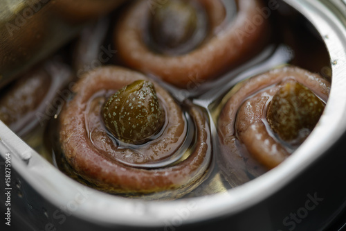 Anchovy rolls with capers in olive oil in tin. Close up