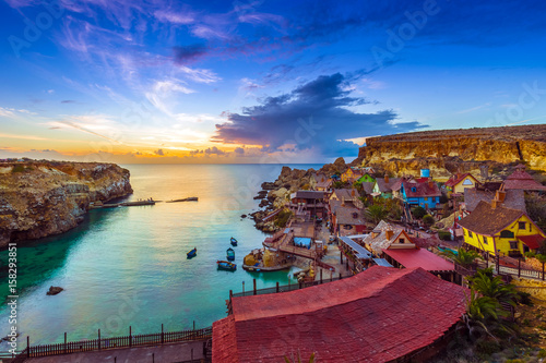 Mellieha, Malta - Skyline view of the beautiful Popeye Village at Anchor Bay at sunset with amazing colorful clouds and sky