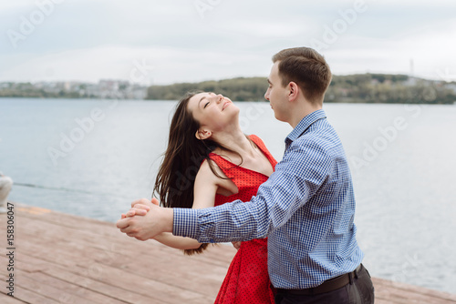 Young beautiful couple in red dress dancing on the background of sunset
