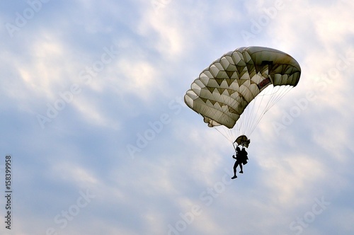 Paracadutista in atterraggio in controluce con cielo nuvoloso