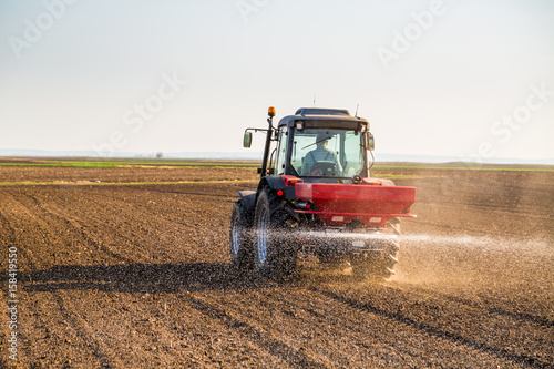 Farmer fertilizing arable land with nitrogen, phosphorus, potassium fertilizer