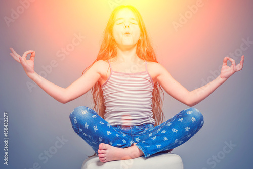 Girl with long hair meditating in a lotus pose in the sunlight