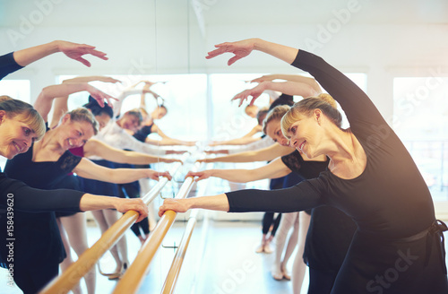 Smiling adult women doing gymnastics at mirror in class
