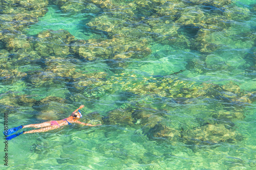 Woman snorkeling over coral reef in famous Hanauma Bay Nature Preserve, Oahu island, Hawaii, USA. Female snorkeler swims in tropical sea with american flag bikini. Watersport activity in Hawaii.