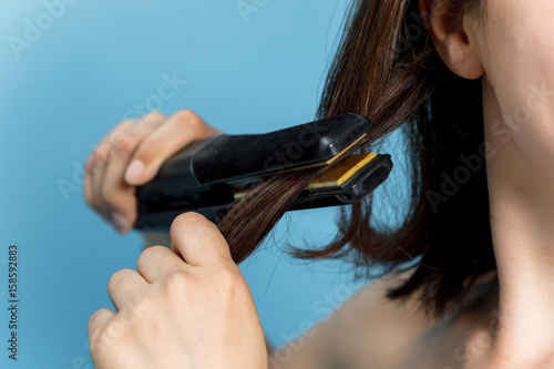 young woman applying a hair iron. hair care concept.