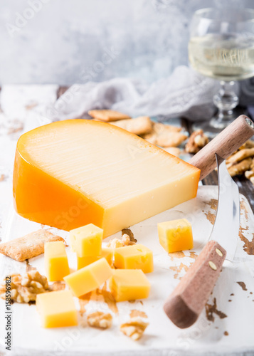 Delicious dutch gouda cheese with cheese blocks, crackers, walnuts and special knife on oud wooden table. Copy space.