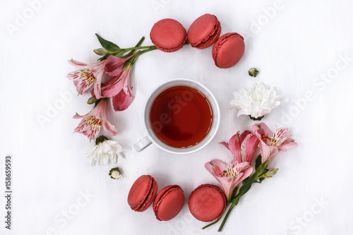 Cup of black tea in a circle of flowers Alstroemeria and almond cookies on white background