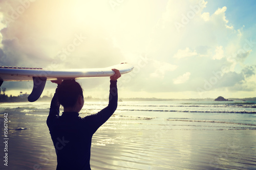 young woman surfer with surfboard ready to surf on a beach