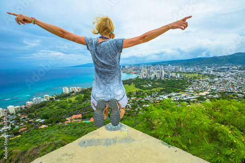 Happy hiker jumping. Hawaiian hiking by popular Diamond Head hike. Traveler freedom woman. Honolulu and Waikiki Beach Skyline from Diamond Head State Monument and Park. Oahu Island in Hawaii, USA.