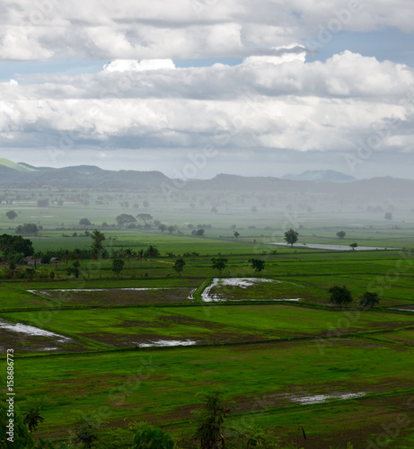 landscape panorama with view of green field and mountains on rainy day