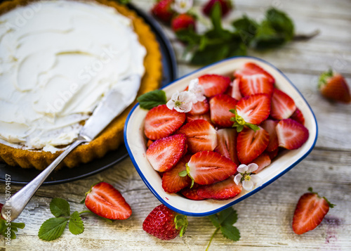 Delicious sponge cake with fresh strawberries and mascarpone on a wooden background.