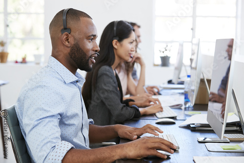 Young black man with headset working at computer in office