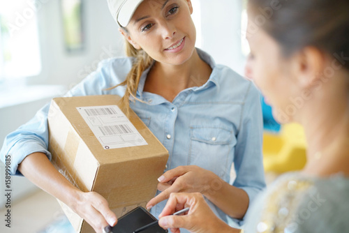 Delivery woman handing package to customer against signature