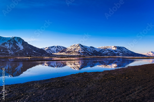landscape of the Arctic Ocean and reflection with blue sky and winter mountains with snow , Norway, Spitsbergen, Longyearbyen, Svalbard
