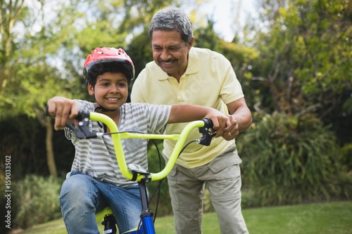 Grandfather assisting grandson while riding bicycle