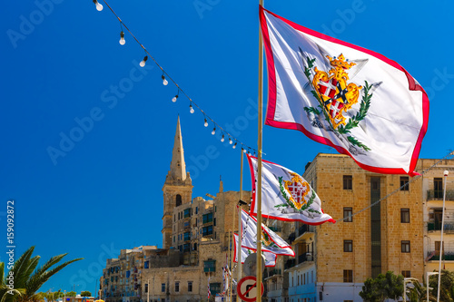 Festively decorated street with flags of all the Grand Masters of the Sovereign Military Order of Malta in the old town of Valletta, Malta