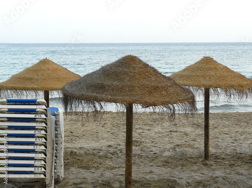 Tres sombrilas de brezo en la playa