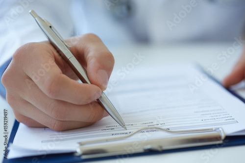 Close up of doctor's hands taking notes. Ward round, patient visit check, medical calculation and statistics concept. Physician ready to examine patient
