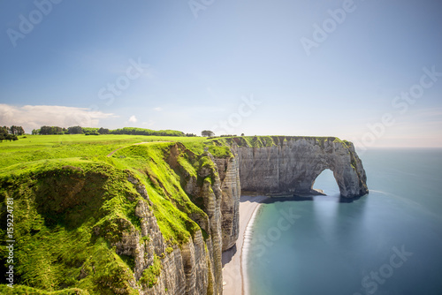 Landscape view on the famous rocky coastline near Etretat town in France during the sunny day. Long exposure image technic with soft water