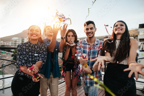 Young people enjoying rooftop party with confetti