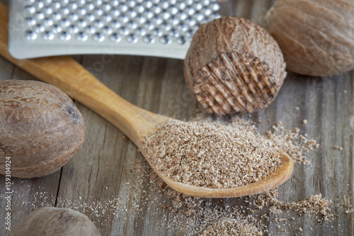 Group of nutmeg seeds with nutmeg powder in wooden spoon 