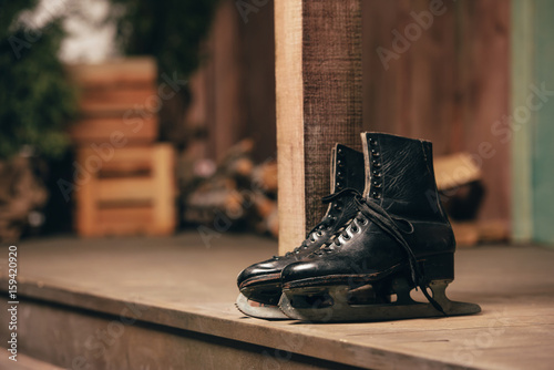 Closeup view of black old ice skates lying on wooden porch