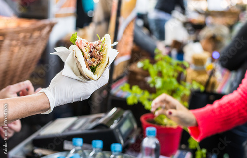 Chef handing a tortilla to a foodie at a street food market