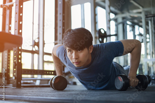 Młody Azjatycki mężczyzna ćwiczy w sprawności fizycznej gym z racy światłem