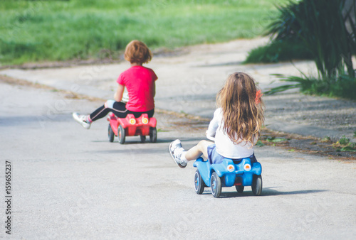 Children playing on the street driving toy cars