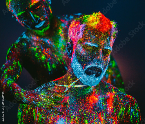 Concept. A bearded man in Barbershop. A stylish bearded man is trimmed in Barber Shop. The man is decorated in ultraviolet powder.