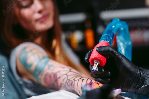 Professional tattoo artist makes a tattoo on a young girl's hand.