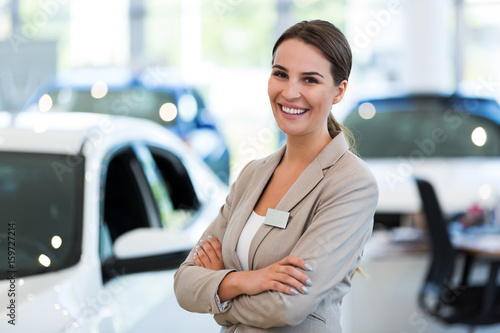 Confident young car dealer standing in showroom 