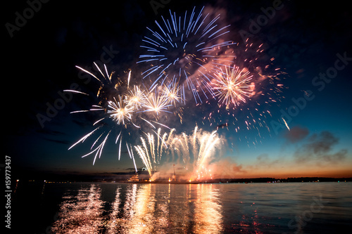 Holiday fireworks above water with reflection on the black sky background