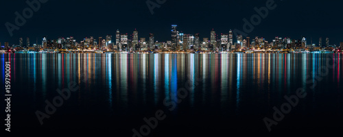 Fantastic nighttime panoramic city view with illuminated skyscrapers reflected on calm water. Ultra wide night time panoramic view of Seatle.