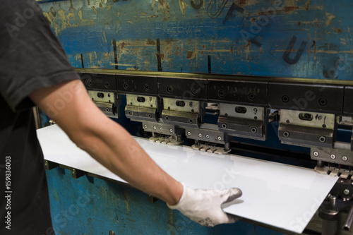 Worker bending a sheet of aluminium.